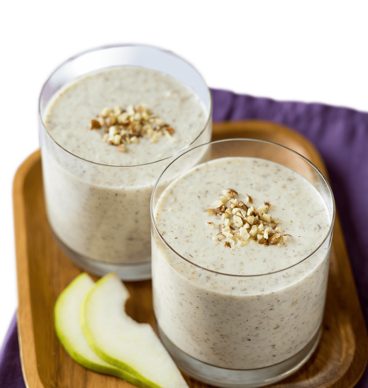 Two glasses of creamy pear and hazelnut milk smoothie topped with chopped nuts, presented on a wooden tray for a rich, nutty treat.
